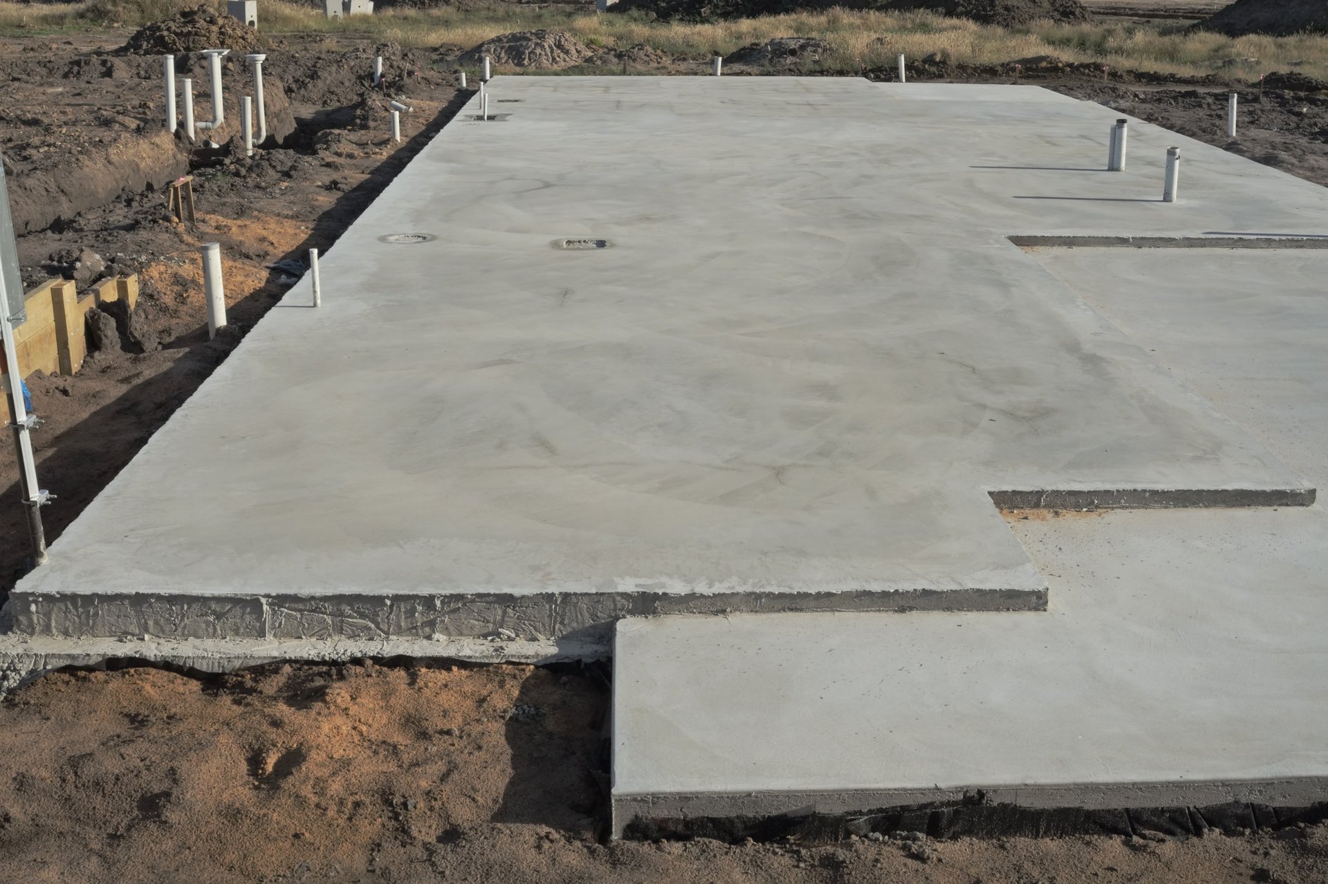 Reinforced concrete foundation with utility pipes prepared for slab placement