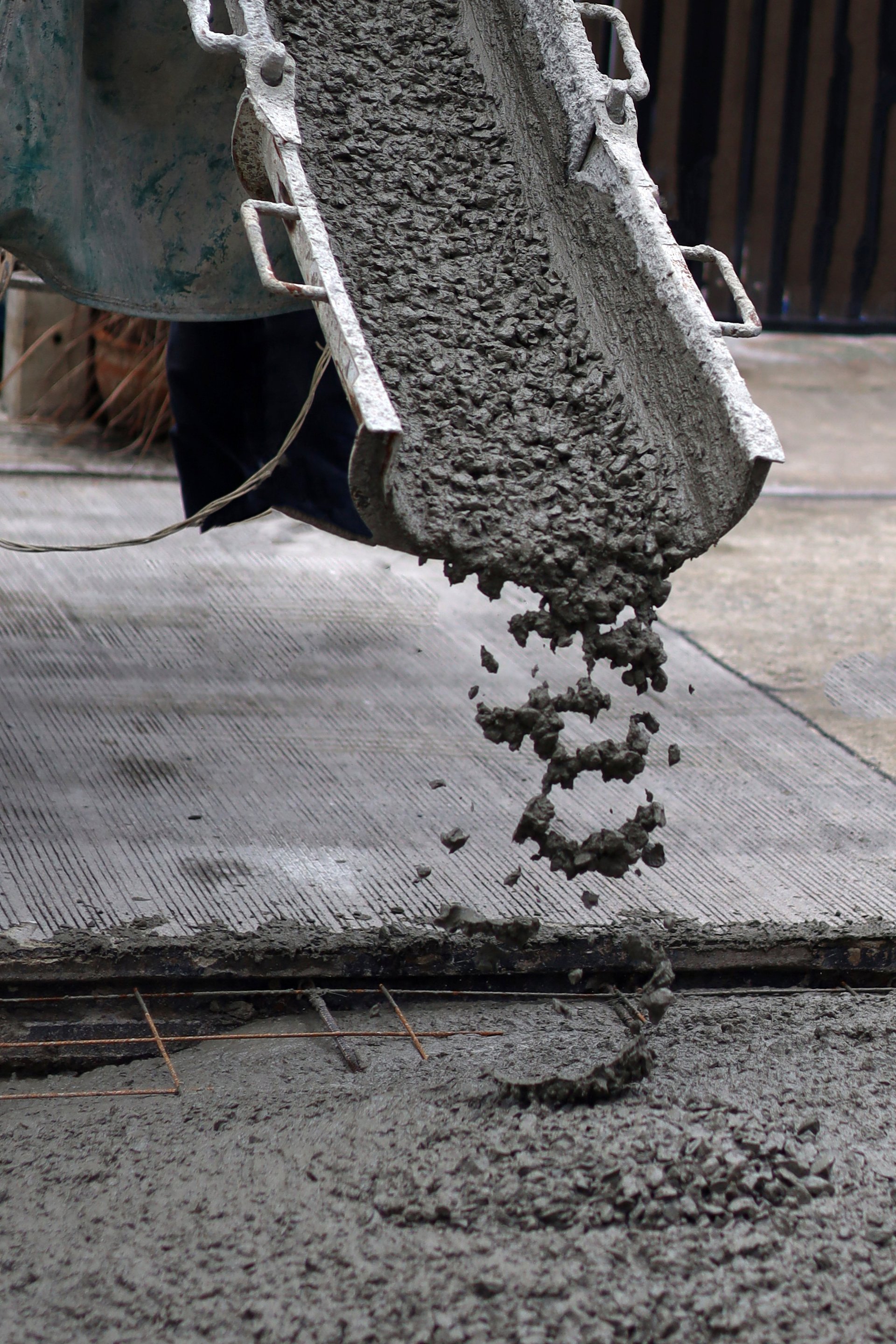 Wet cement pouring from a mixer truck chute onto a steel wire mesh for road construction