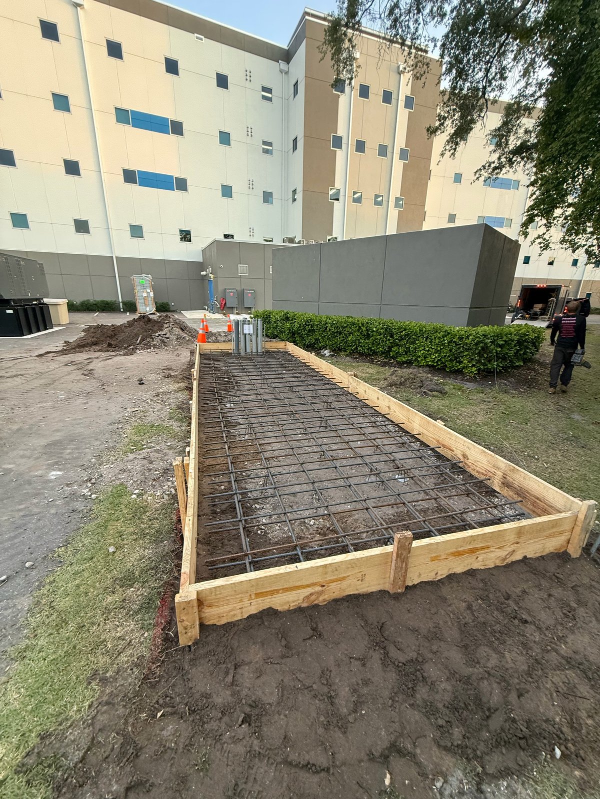 Concrete foundation with wooden frame and rebar reinforcement at construction site near apartment buildings